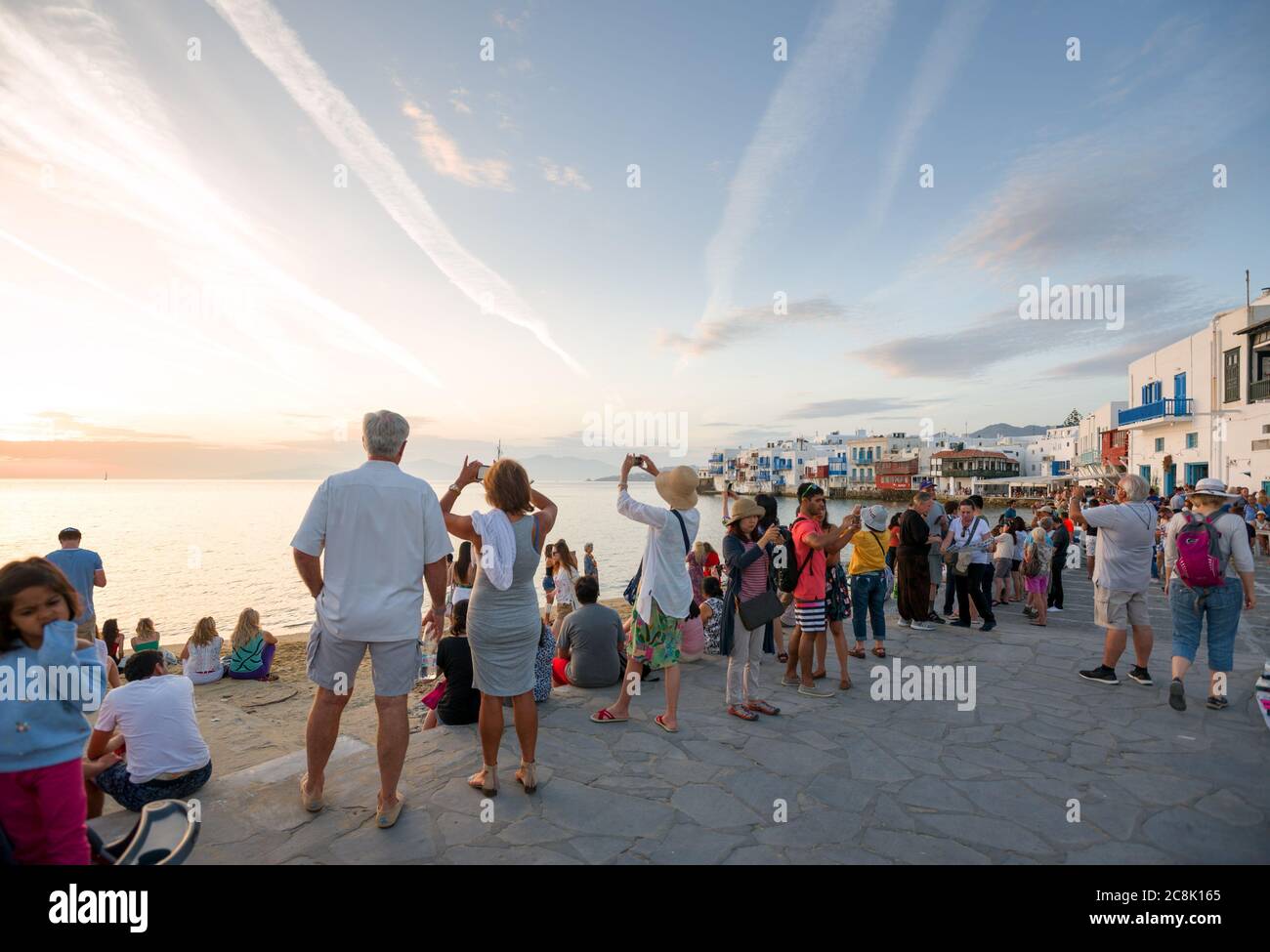 Molte persone guardano il tramonto sulla passeggiata di Mykonos Foto Stock