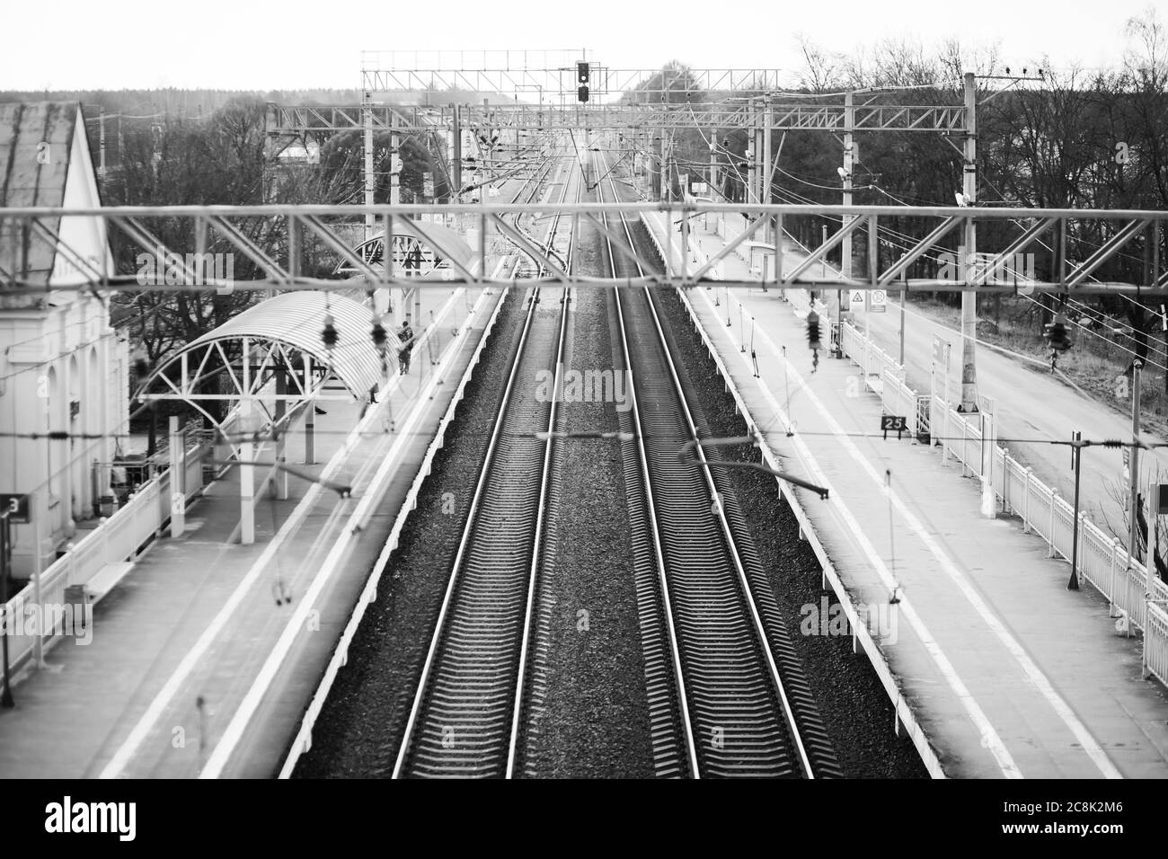 Immagine in bianco e nero di lunghe piste ferroviarie e stazioni a metà vuoto. Attesa e tristezza. Foto Stock