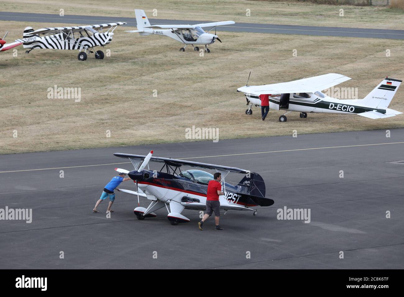 Gera, Germania. 25 luglio 2020. I membri dell'equipaggio spingono un aereo biplanare (anteriore) Pitts S2S sul grembiule dell'aerostazione Gera-Leumnitz per il rifornimento, ai Campionati tedeschi di aerobica motorizzata. In sei giorni 32 partecipanti hanno lottato qui per il titolo. Credit: Bodo Schackow/dpa-zentralbild/dpa/Alamy Live News Foto Stock