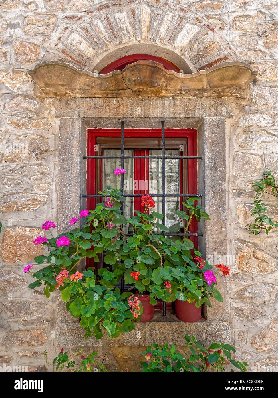 Effimero ed Eterno. Fiori di geranio colorati su una finestra secolare. Camminando nei vicoli medievali di Pyrgi, Isola di Chios, Grecia Foto Stock