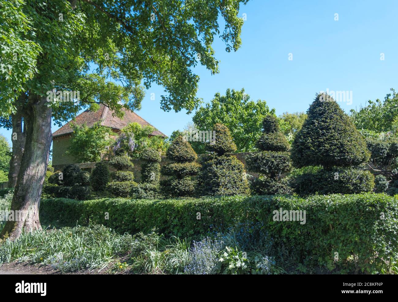 Giardino topiario con colombaia in background, siepi e letto di fiori a Eastcote House Gardens, Eastcote Middlesex, Londra nord-occidentale. Foto Stock