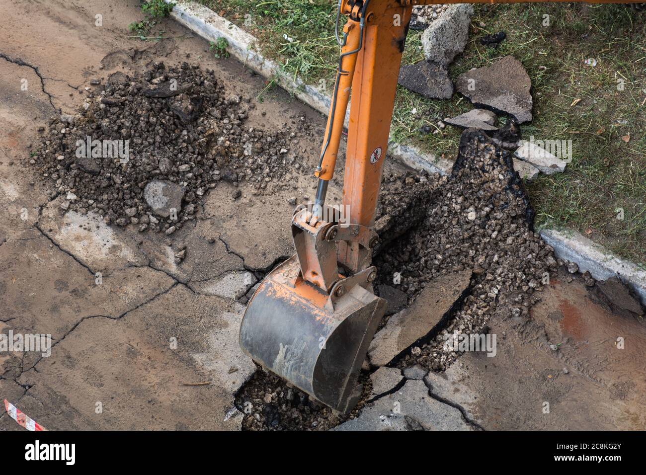 L'escavatore rompe l'asfalto. Rottura di un tubo di alimentazione dell'acqua. L'acqua ha lavato via l'asfalto. Foto Stock