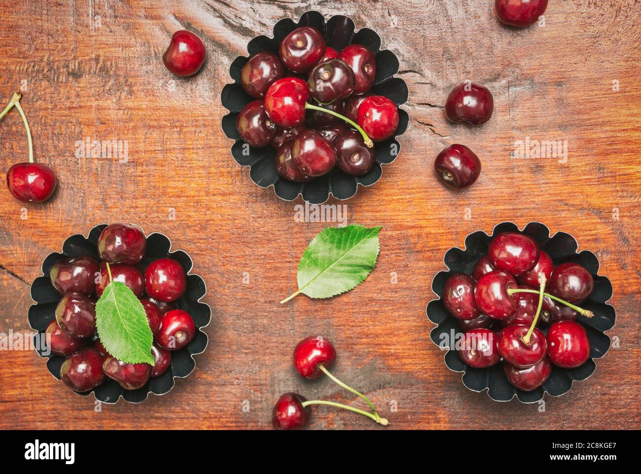 Composizione piatta con ciliegie dolci su tavola di legno, spazio per testo. Foto Stock