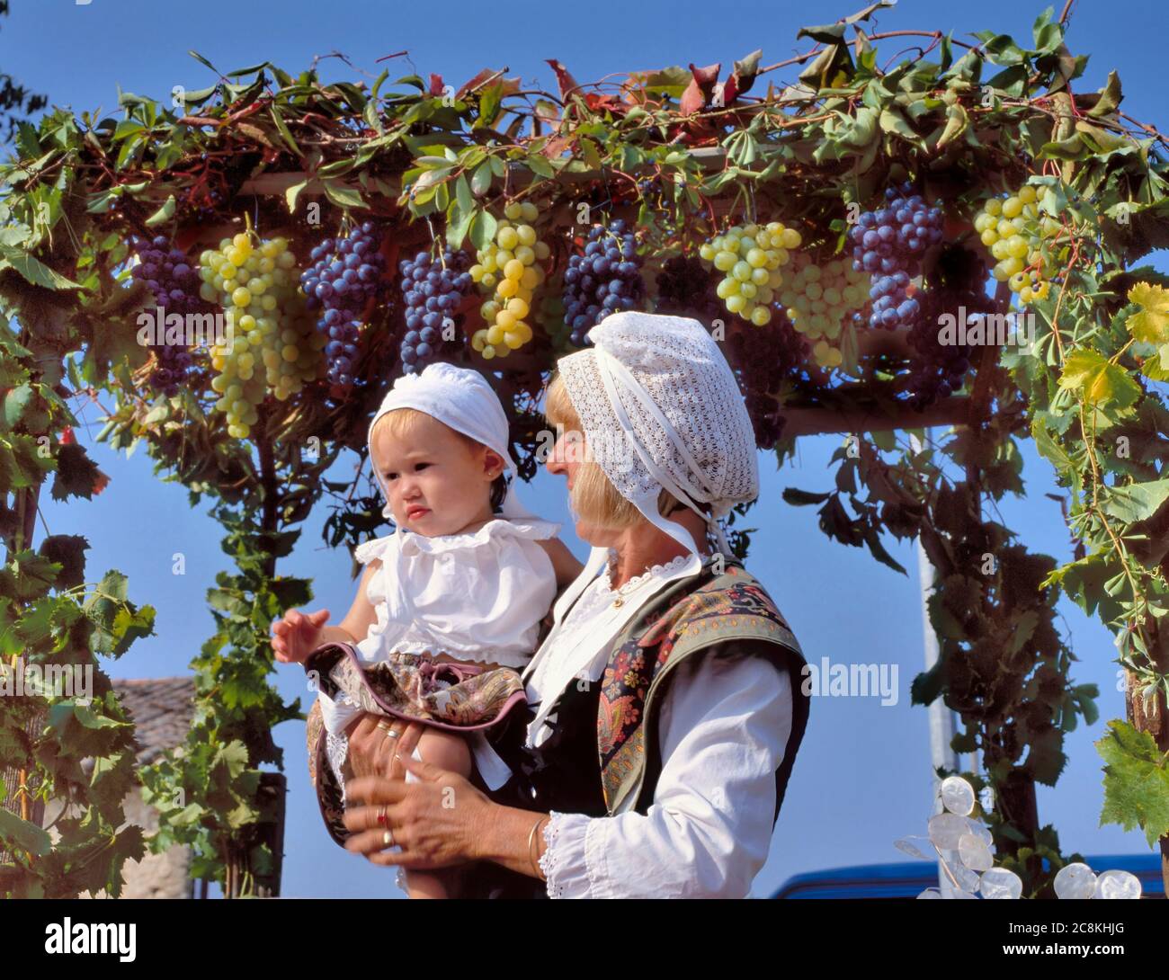 Coustelet, Francia-settembre 29,2019: Fine della festa di vendemmia del vino con la madre e la ragazza che tiene sul suo braccio mentre serve il vino in costume tradizionale Foto Stock