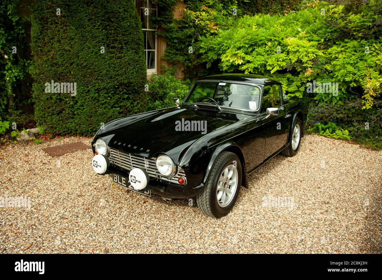 Triumph TR4 parcheggiato su una strada in ghiaia di fronte una grande casa Foto Stock