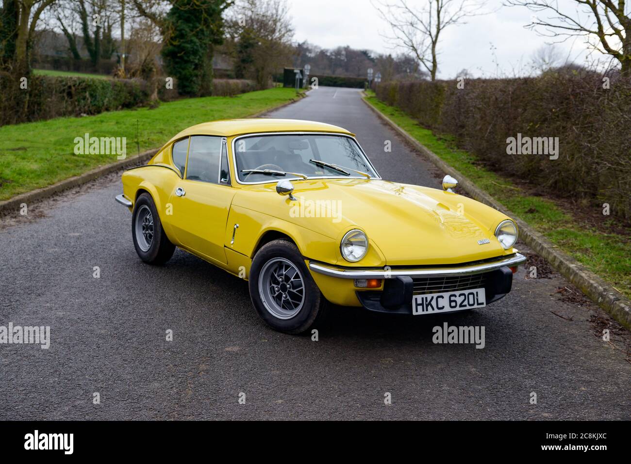 Triumph GT6 giallo parcheggiato su una corsia di campagna in inverno Foto Stock