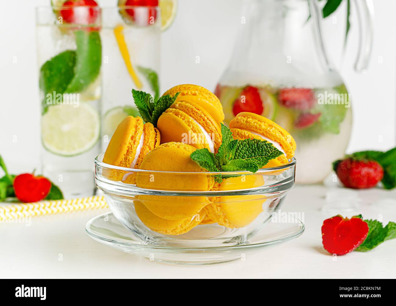 Macaroni gialli in un recipiente di vetro su sfondo bianco. Concetto di dessert francese Foto Stock