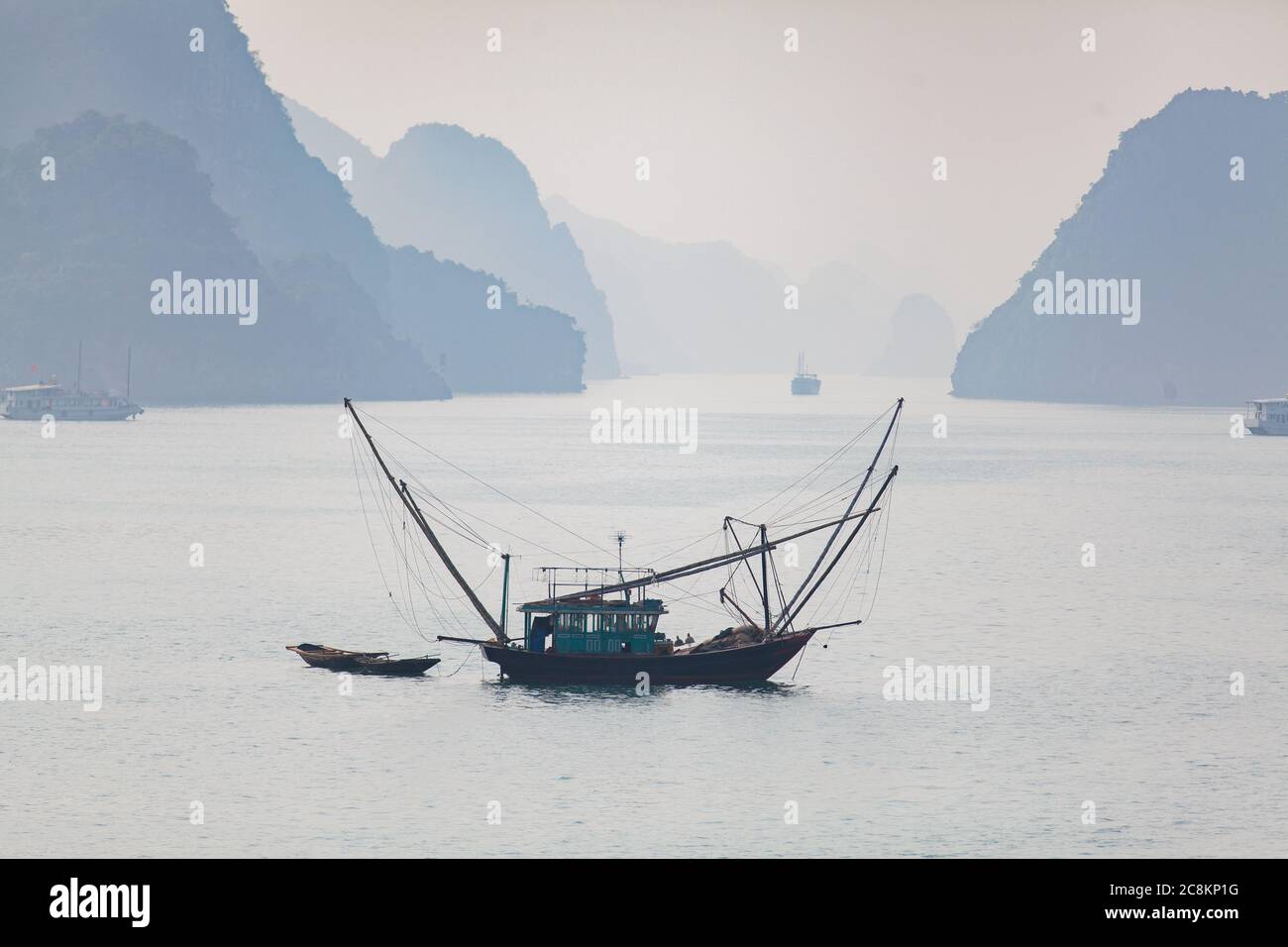 Ha Long Bay, Vietnam, isole calcaree sormontate da foreste pluviali, barche da pesca Foto Stock