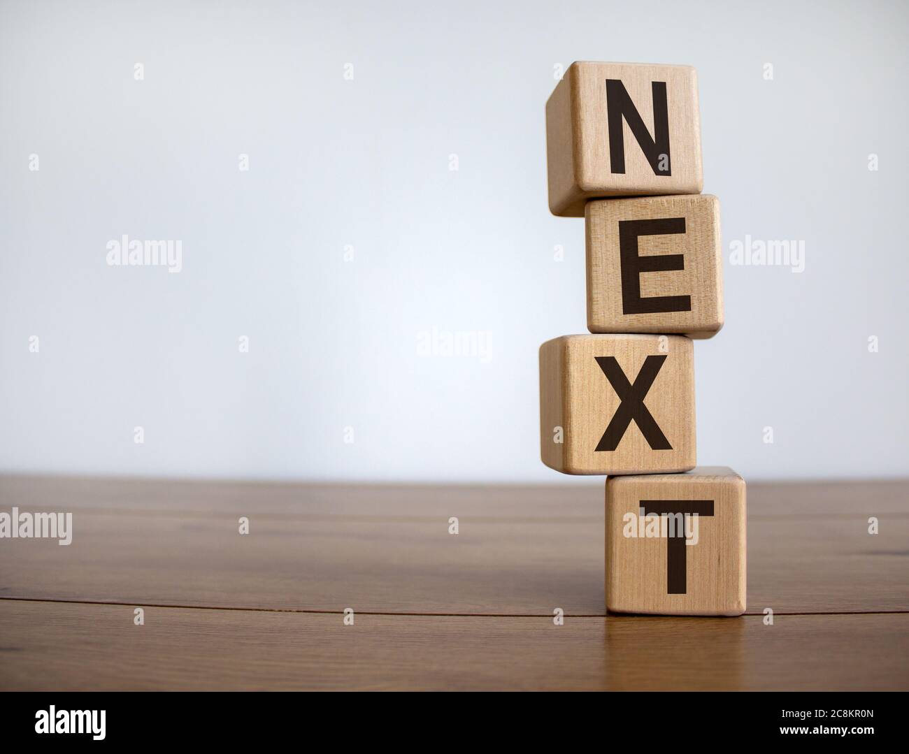 Concetto parola 'prossimo' su cubi su un bel tavolo di legno. Sfondo bianco. Concetto aziendale. Spazio di copia. Foto Stock