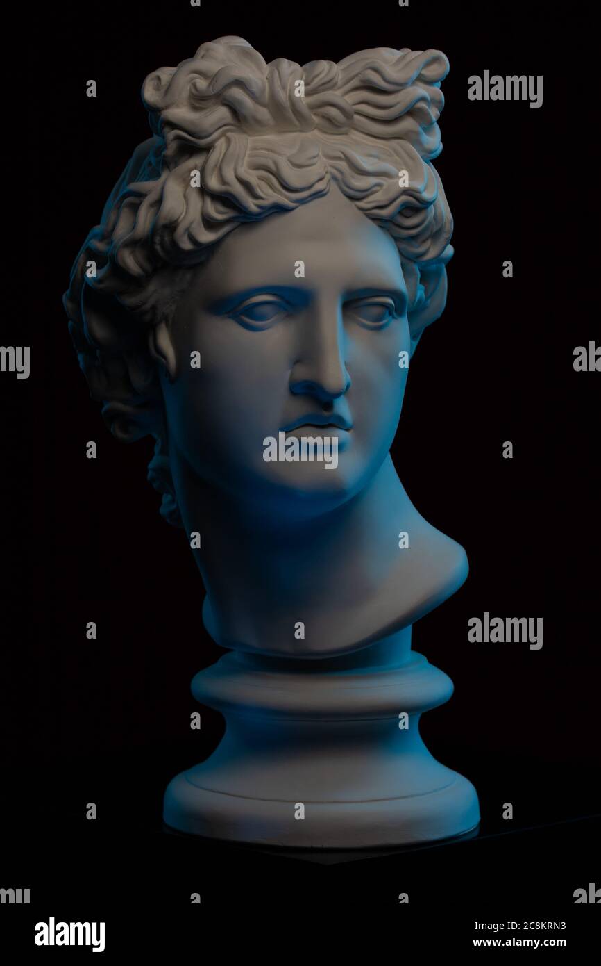 Statua in gesso di un busto di Apollo Belvedere in blu luce locale su sfondo nero Foto Stock