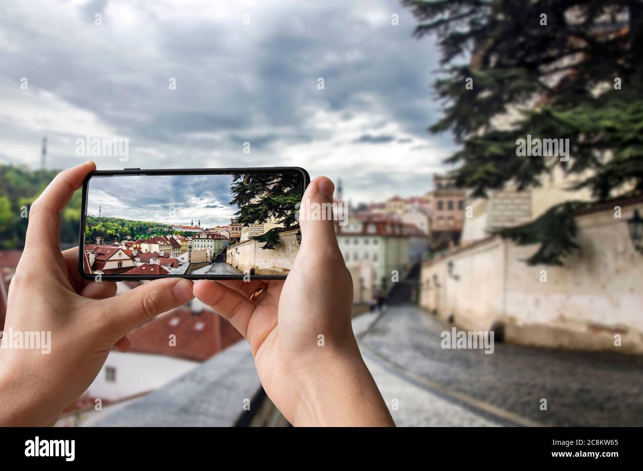 Turista che scatta foto della vista della strada a Praga, Repubblica Ceca. Uomo che tiene il telefono e fotografare la strada con una splendida vista sulla città storica Foto Stock