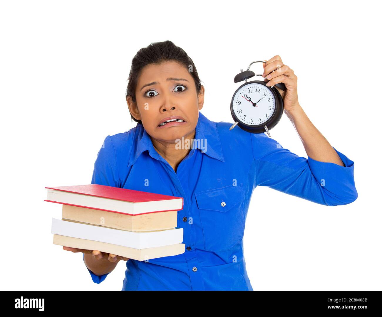 Ritratto di una giovane donna nervosa impegnata che porta una pila di libri e sveglia sensazione stressata da progetto scadenza isolato su sfondo bianco. Foto Stock