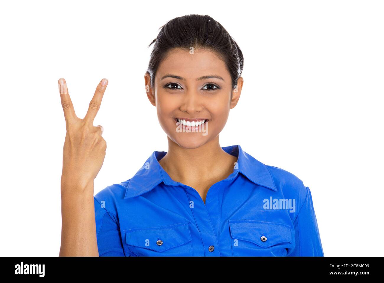 Ritratto di una giovane donna sorridente felice che dà la vittoria di pace o due gesti di segno, isolato su sfondo bianco. Foto Stock