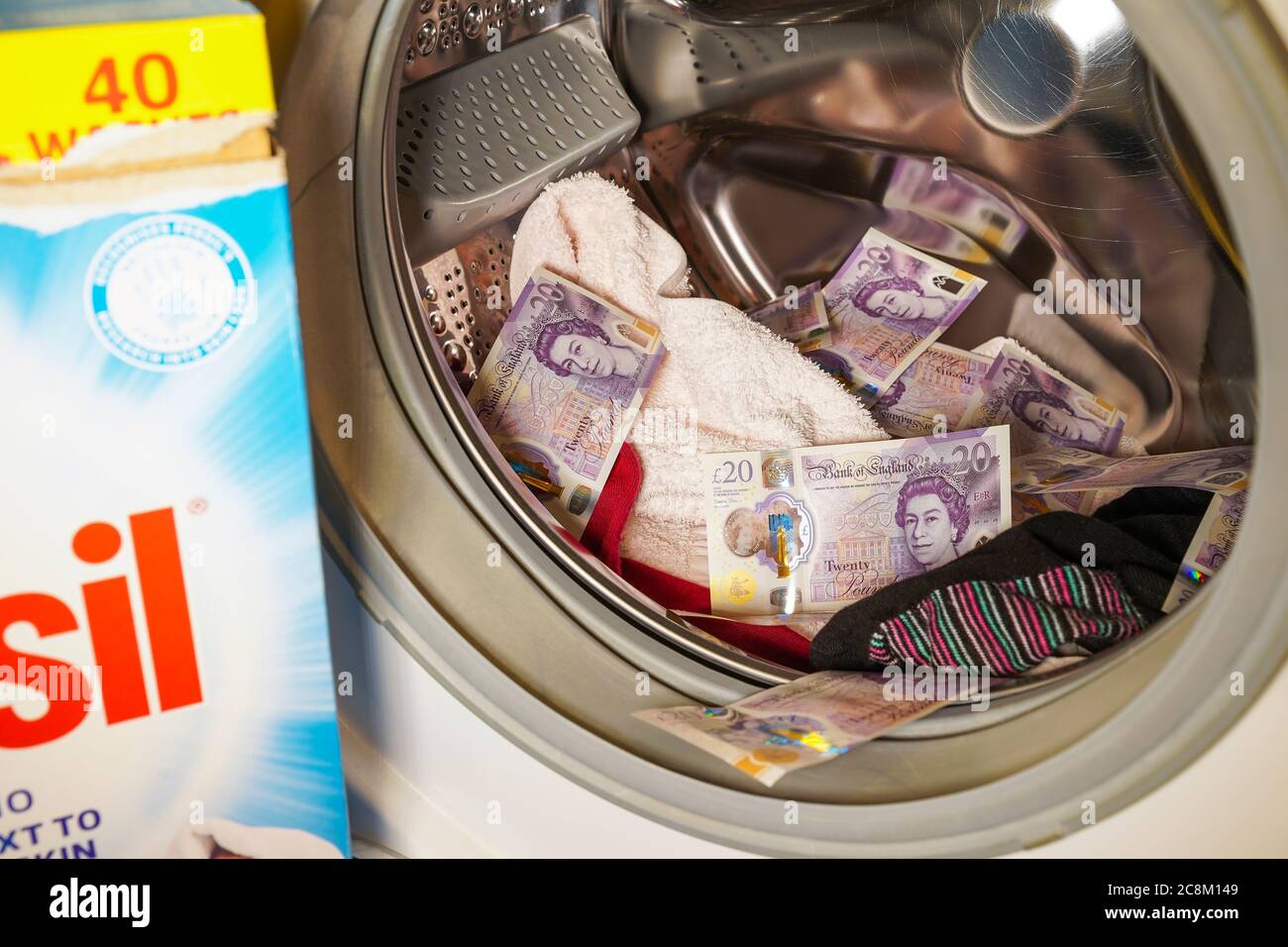 Primo piano di valuta britannica, banconote da 20 sterline, all'interno del cesto della lavatrice automatica. Concetto di riciclaggio di denaro, riciclaggio di denaro sporco di reato. Foto Stock
