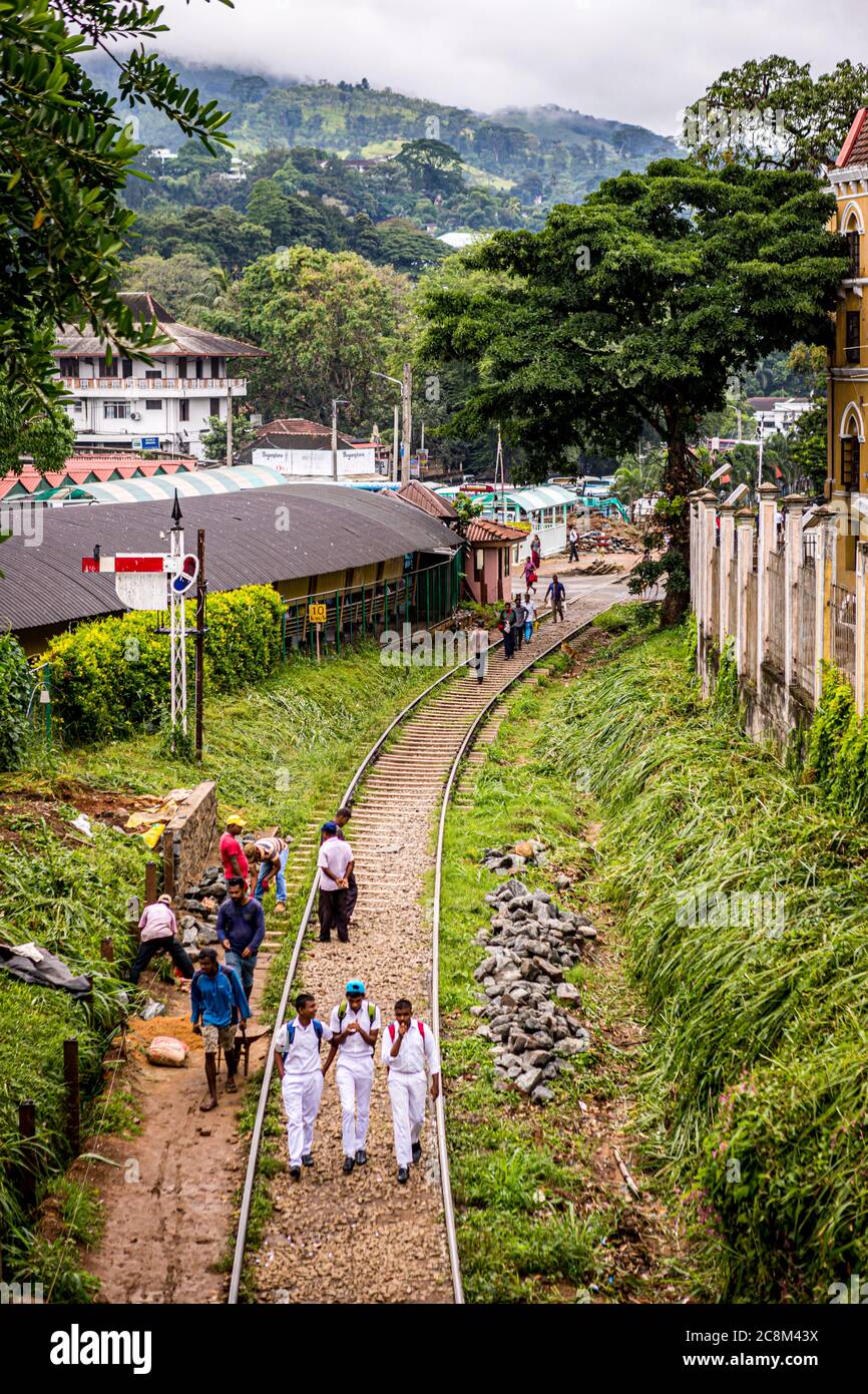 Gli studenti camminano lungo i binari del treno fuori dalla stazione ferroviaria di Kandy in Sri Lanka Foto Stock