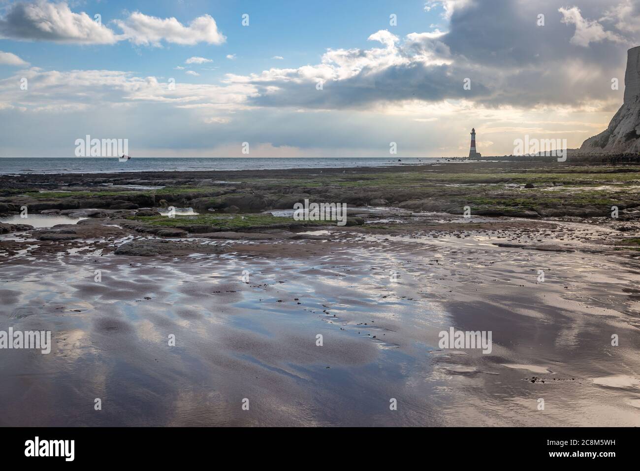 Guardando oltre la spiaggia vicino a Eastbourne con la bassa marea, verso il faro di Beachy Head Foto Stock