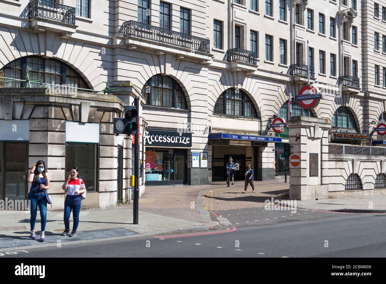 Stazione della metropolitana di Baker Street. Due giovani donne usano la traversata pedonale per attraversare Marylebone Road, Londra, Inghilterra, Regno Unito Foto Stock