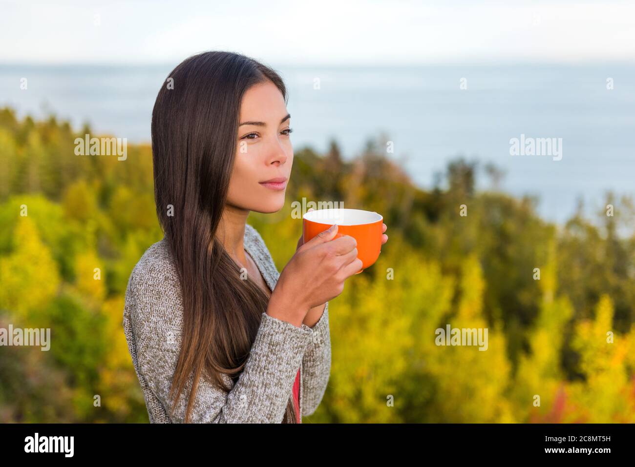 Natura all'aperto caffè bere donna rilassante nella foresta autunno sole godendo il suo caffè mattutino. Felice multirazziale canadese cinese asiatico Foto Stock