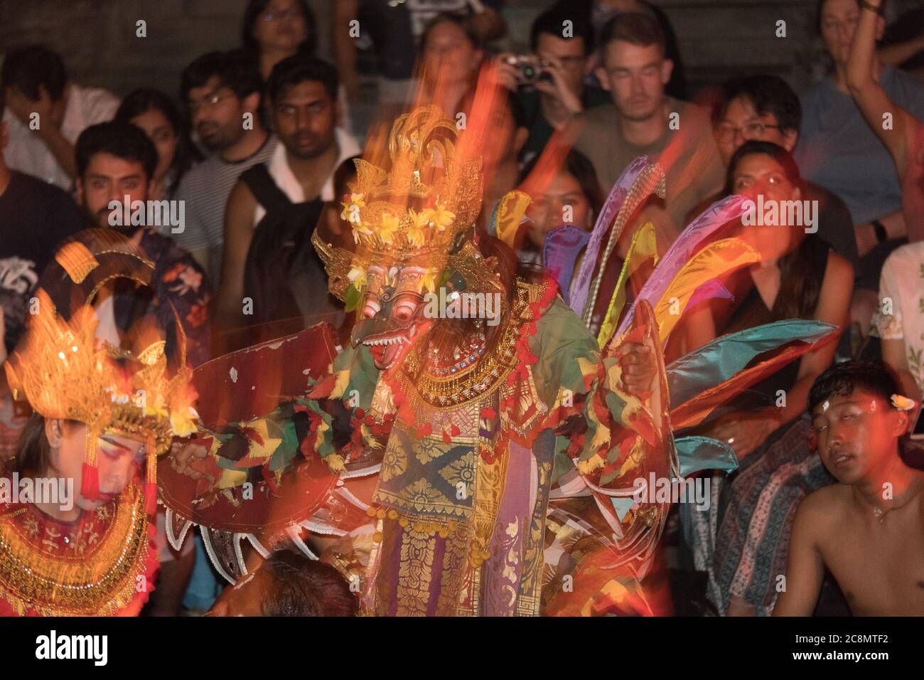 Foto drammatica di ballerini Kecak vestiti con colori colorati e vestiti in costumi tradizionali dai colori vivaci che eseguono la danza balinese del Tempio Ramayana Indù. Foto Stock