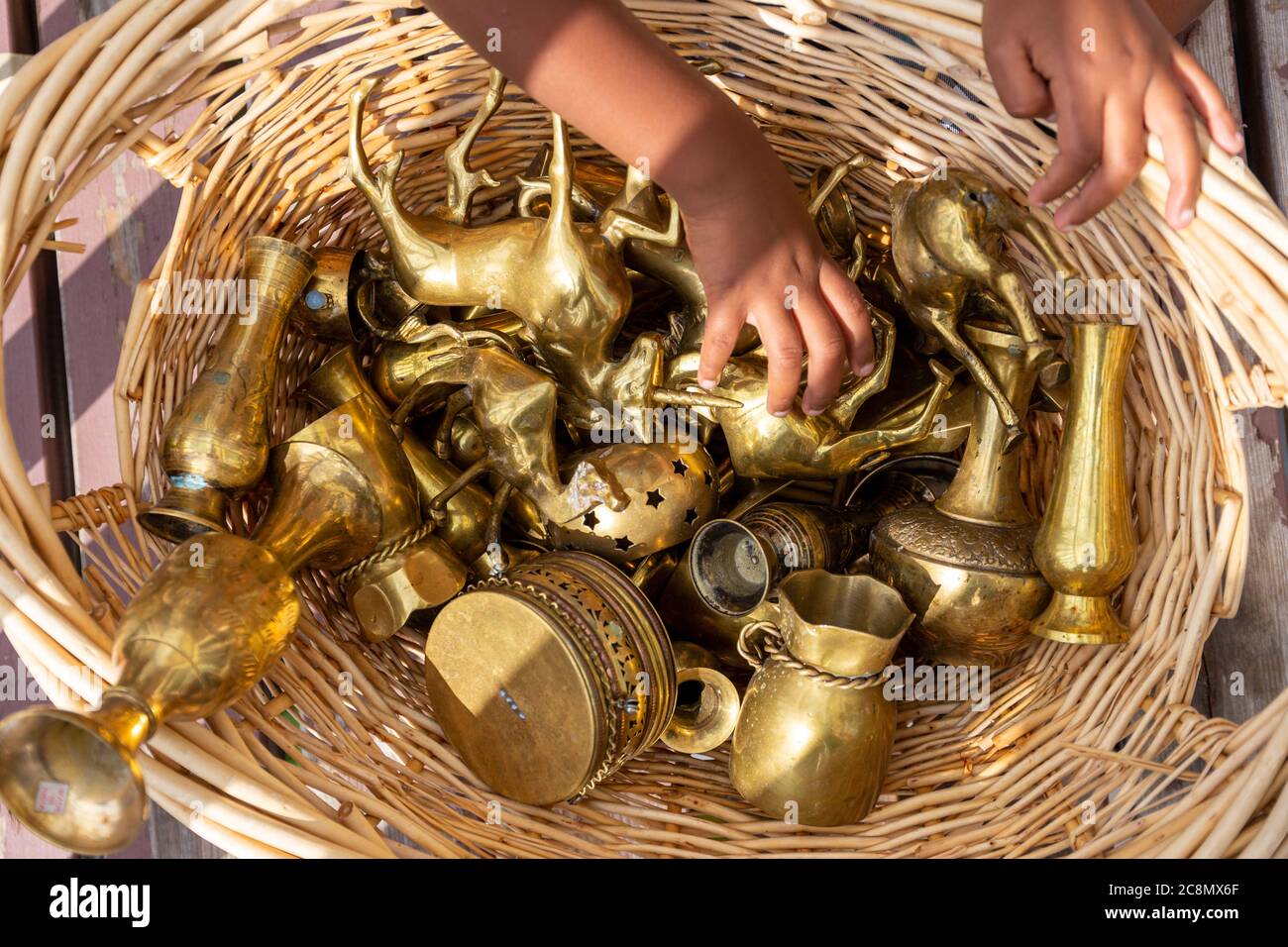 Bambino che gioca con una varietà di oggetti da collezione in ottone Foto Stock