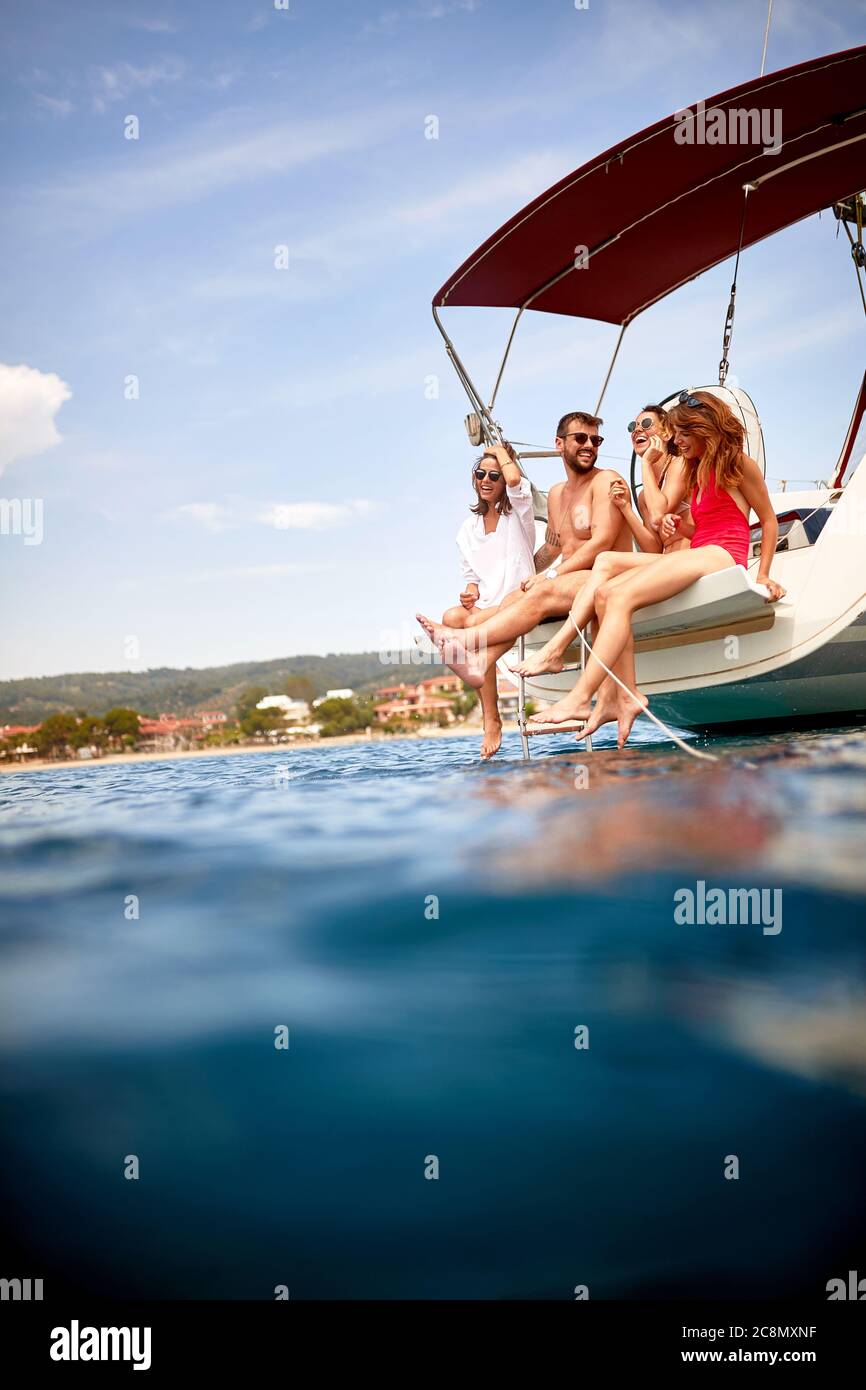 Amici seduti a poppa di uno yacht in condizioni di sole Foto Stock