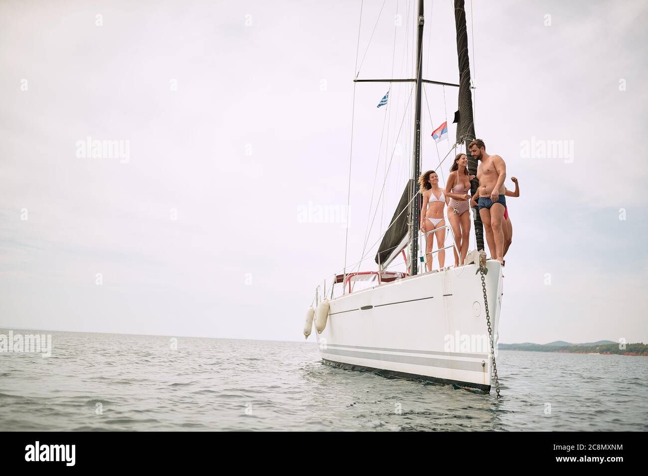 Gli amici si godono il vento su uno yacht in una giornata di sole Foto Stock