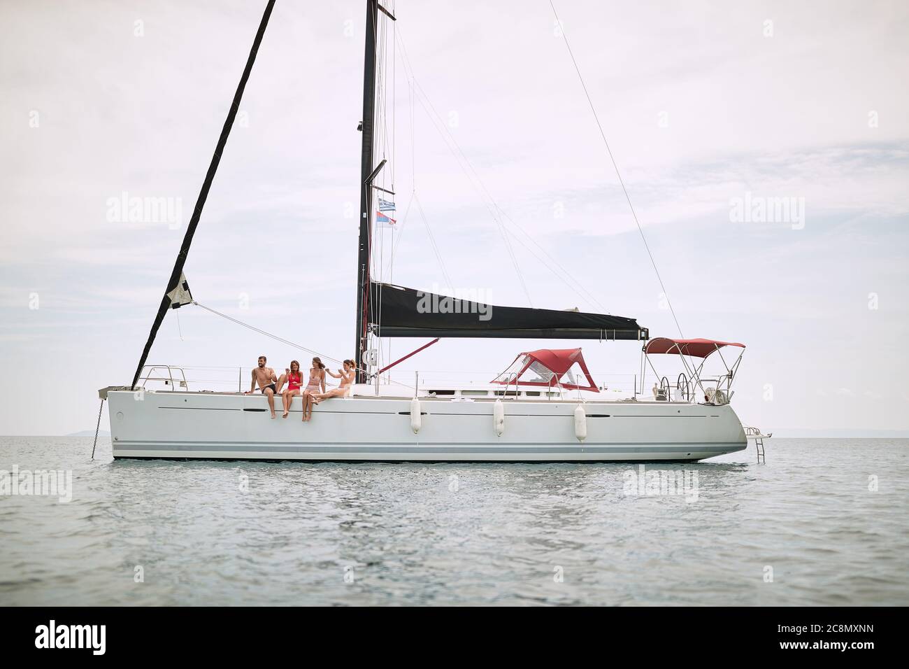 Amici che si rilassano sul ponte di uno yacht in mare aperto in una giornata di sole Foto Stock