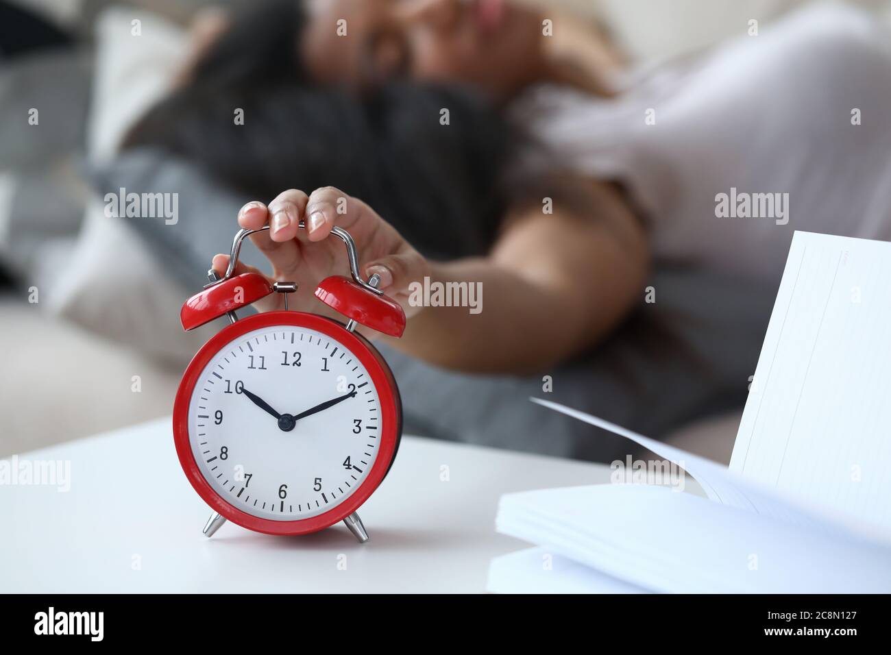 La donna lira sul letto e disattiva la sveglia da vicino Foto stock - Alamy