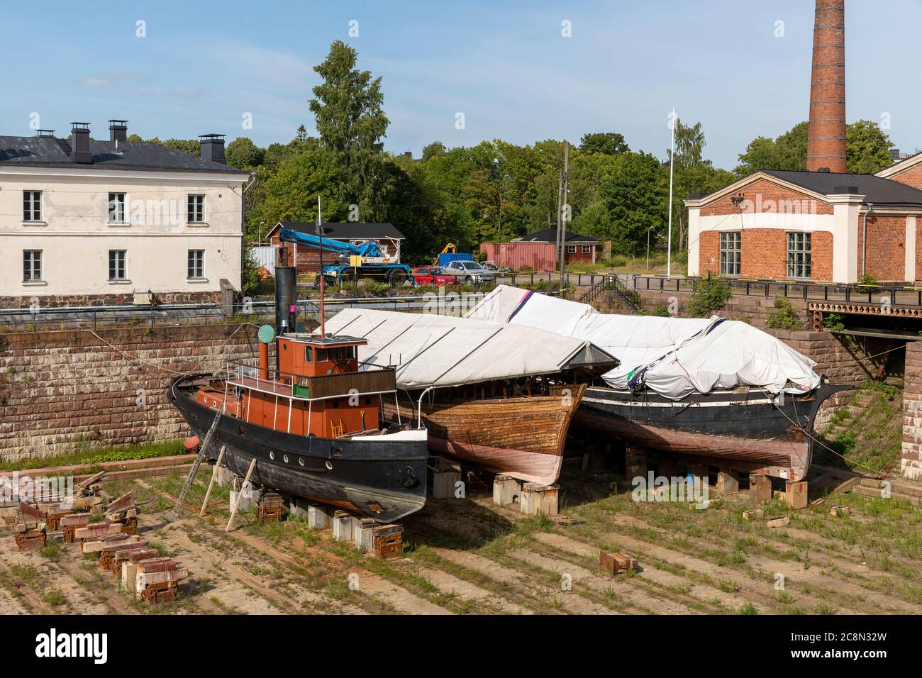 Navi d'epoca in attesa di restauro su un molo a secco sull'isola di Suomenlinna vicino a Helsinki. L'acqua viene portata a bacino quando le navi sono pronte per essere spostate in mare. Foto Stock