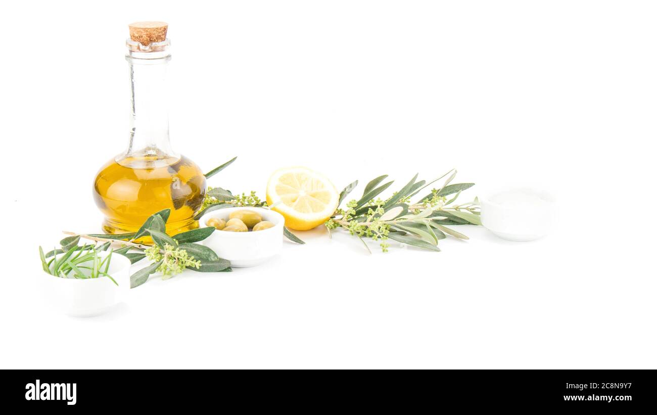 Bottiglia di vetro di olio vergine d'oliva premium, limone e alcune olive con ramificazione di olivo isolata su fondo bianco. Foto Stock