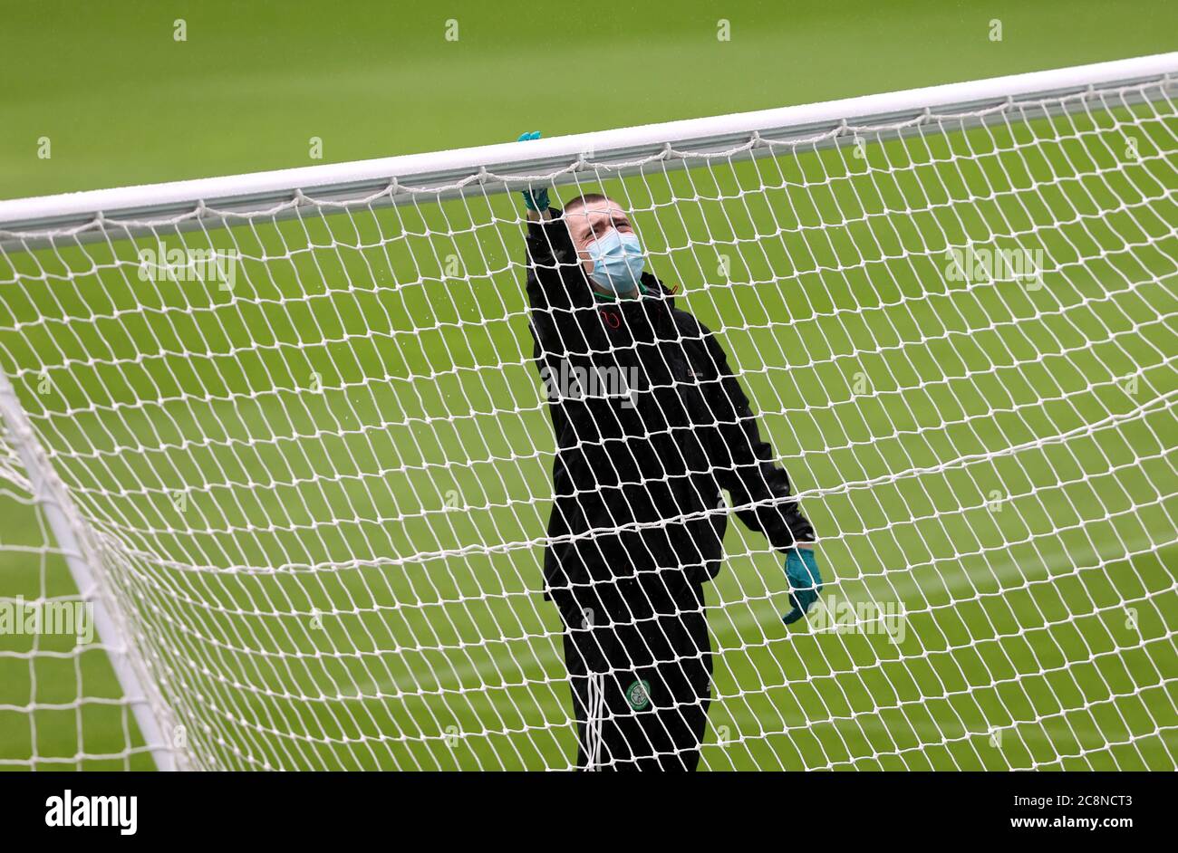 Un membro del personale di terra disinfetta il posto di obiettivo prima della partita amichevole pre-stagione al Celtic Park, Glasgow. Foto Stock