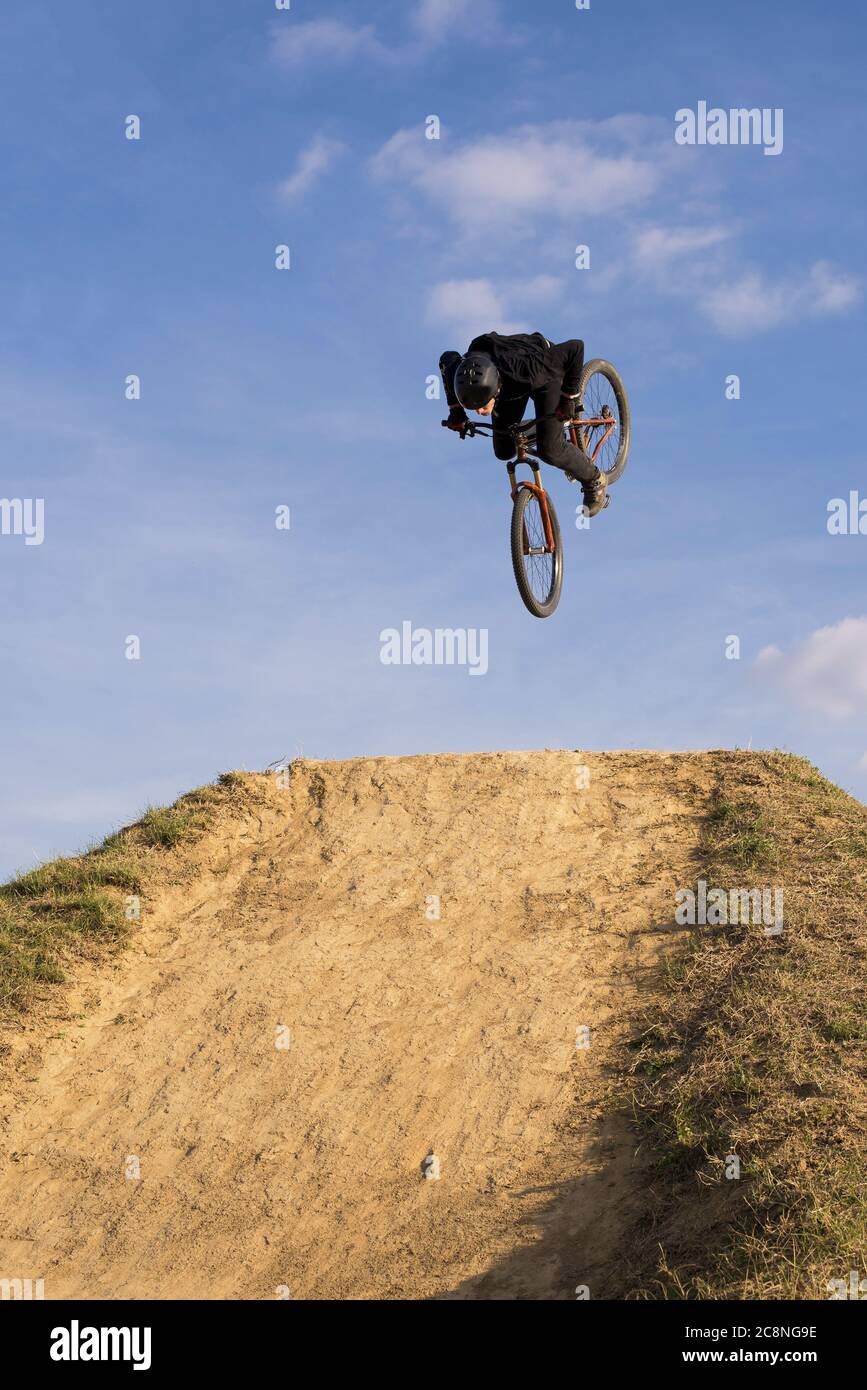 Ripresa verticale di un motociclista che salta su una rampa sfondo blu cielo Foto Stock
