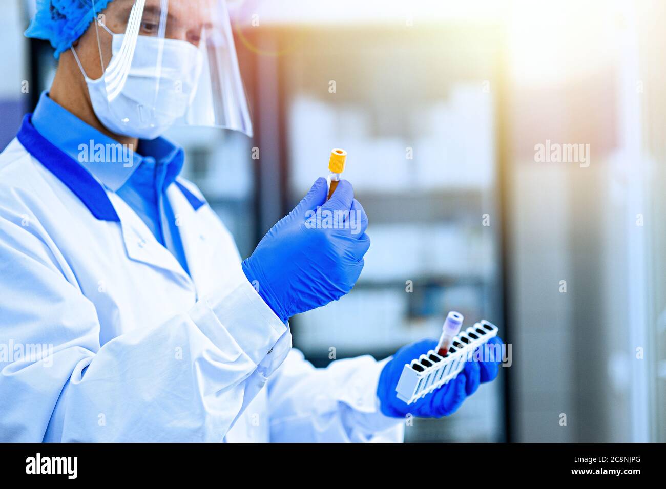 Assistente medico, assistente di laboratorio tiene le provette con biomateriale nelle mani. Un medico, un assistente di laboratorio in una maschera protettiva, vi Foto Stock