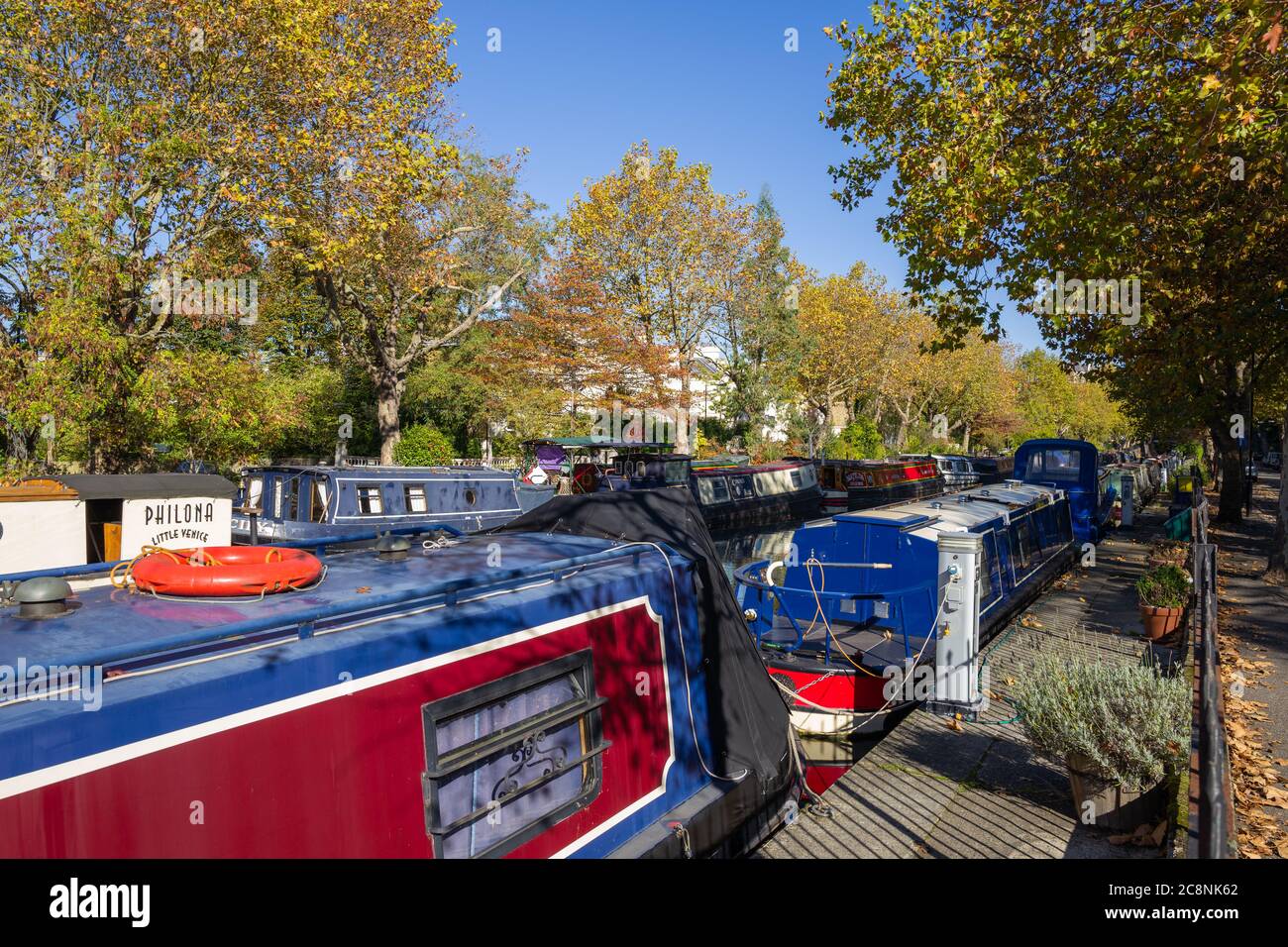 Barche residenziali su canali in una colorata scena autunnale con un cielo blu vivido lungo il canale alberato a Little Venice, Londra ovest. Foto Stock