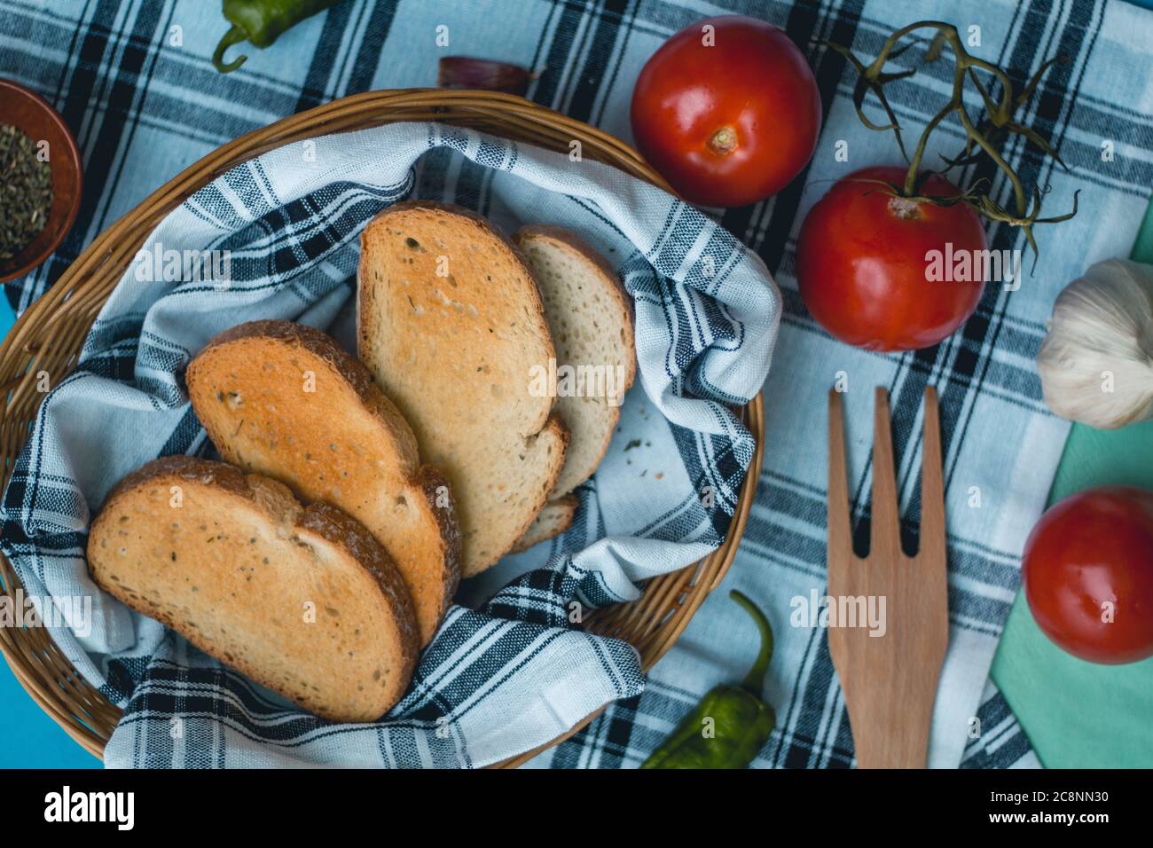 Cibo fresco naturale, ingredienti vegetariani italiani, pasta di spaghetti con aglio e pane tostato su un cesto su un panno da tavola, forchetta di legno di pepe verde Foto Stock