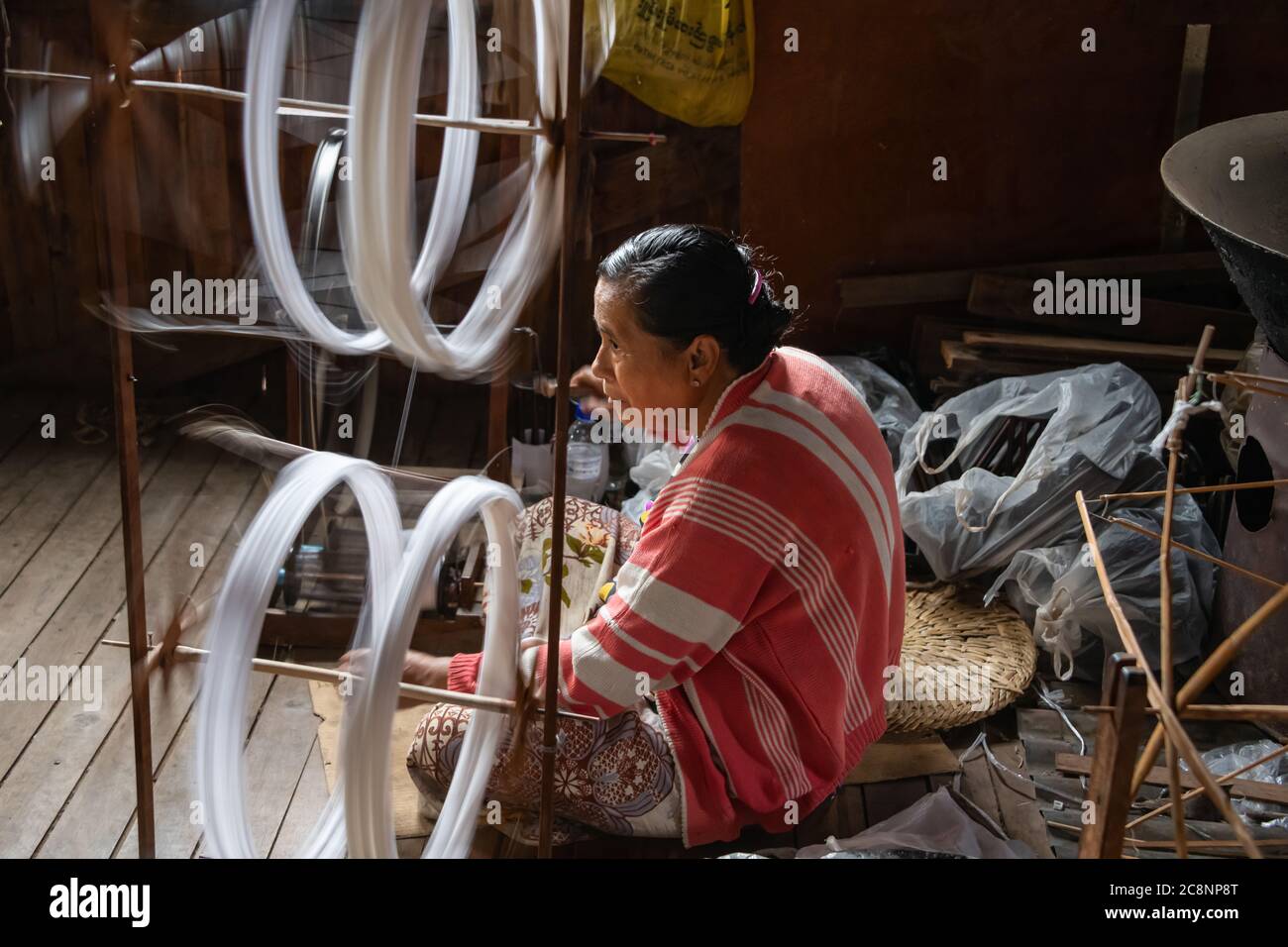 Lago Inle, Myanmar - Febbraio 2020: La donna birmana gira il filo su una ruota di filatura tradizionale nel villaggio locale. Fibre di loto e di seta sono tessute per Foto Stock