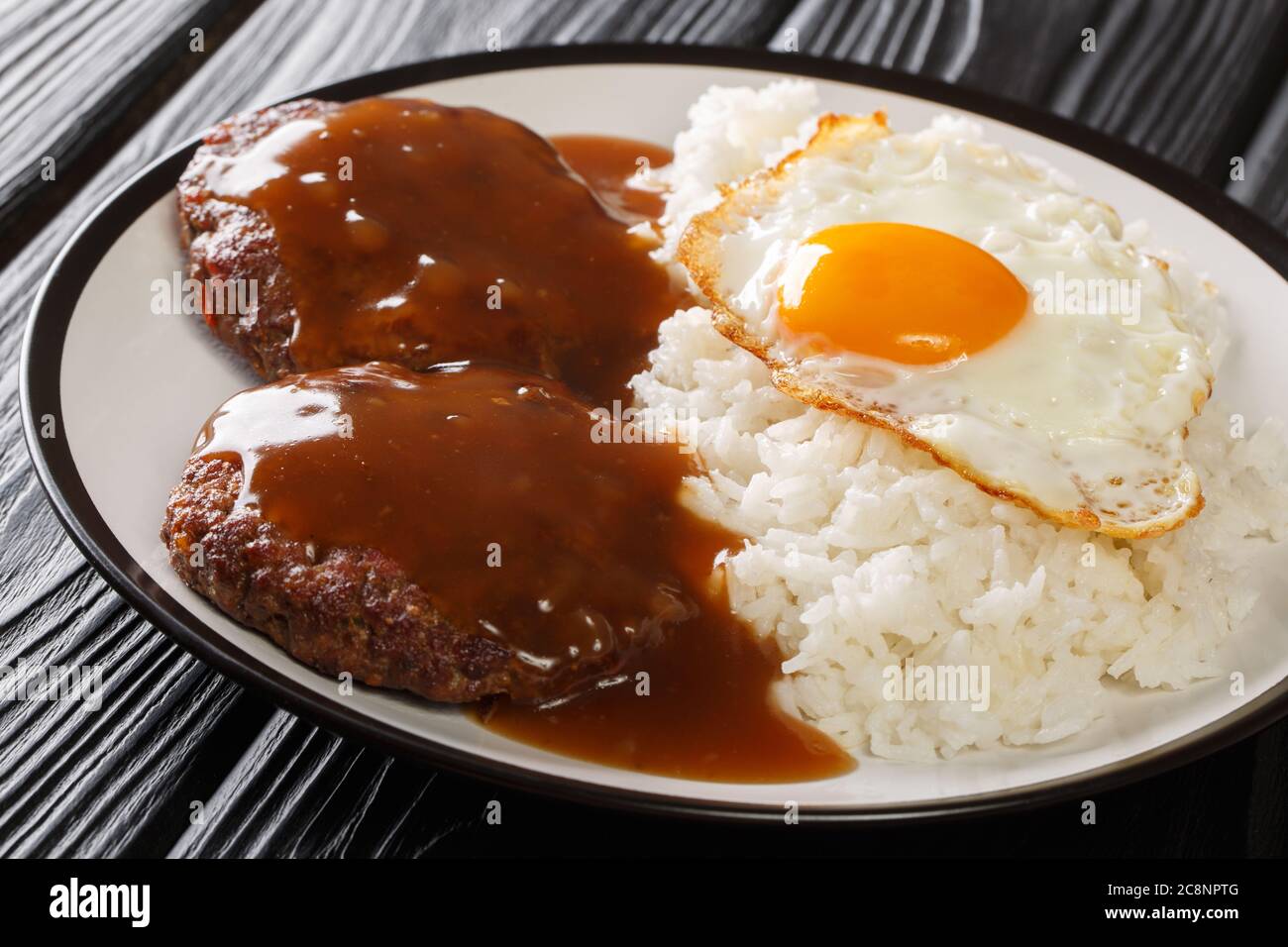 La ricetta del Loco Moco è un delizioso piatto hawaiano composto da riso bianco, una succulenta polpetta di hamburger, un uovo fritto e un primo piano con sugo di carne marrone su un piatto sul Foto Stock