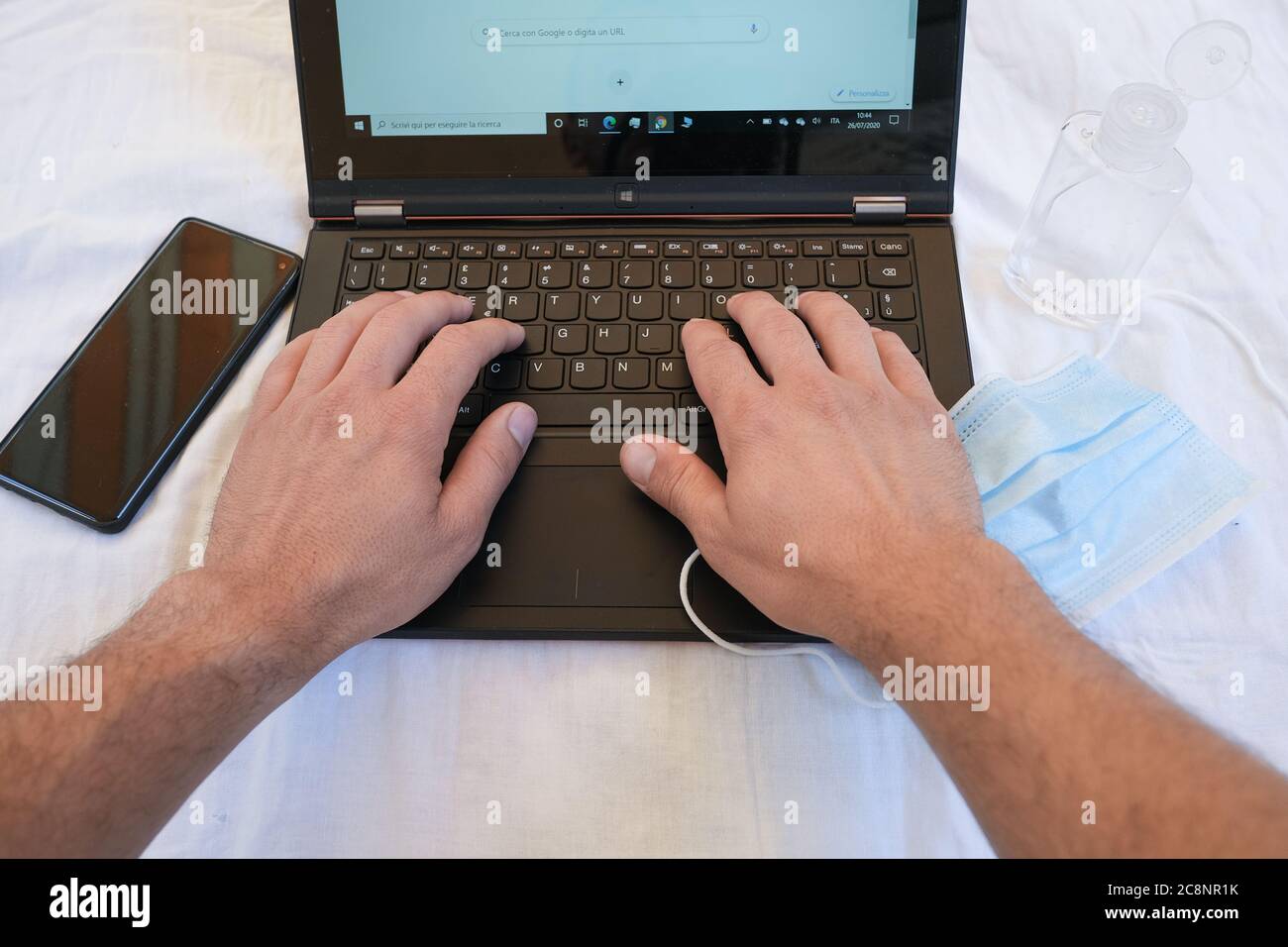 Uomo che scrive su tastiera pc mentre lavora sul commercio di fotoricettore nella malattia del coronavirus Foto Stock