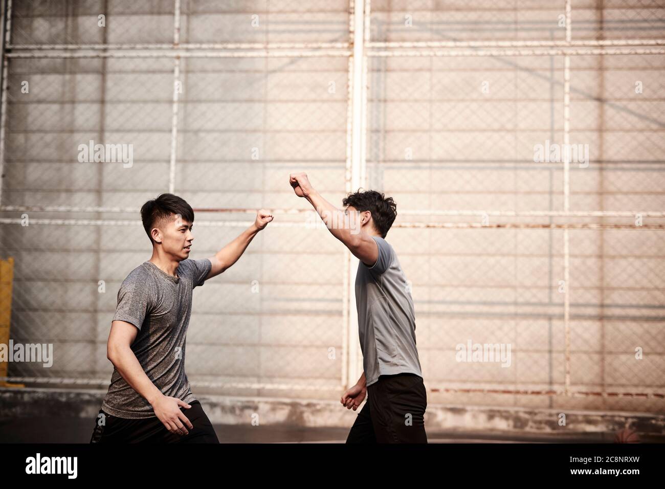 due giovani atleti asiatici che vacillano i pugni celebrando il successo Foto Stock