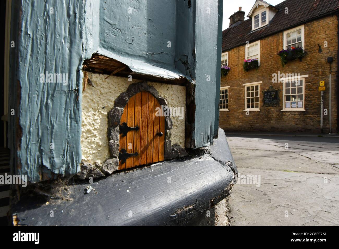 Piccola porta in fondo alla porta principale, al piano terra, ad un negozio a Frome, Somerset. È per la piccola gente, fate o piccoli animali. Foto Stock