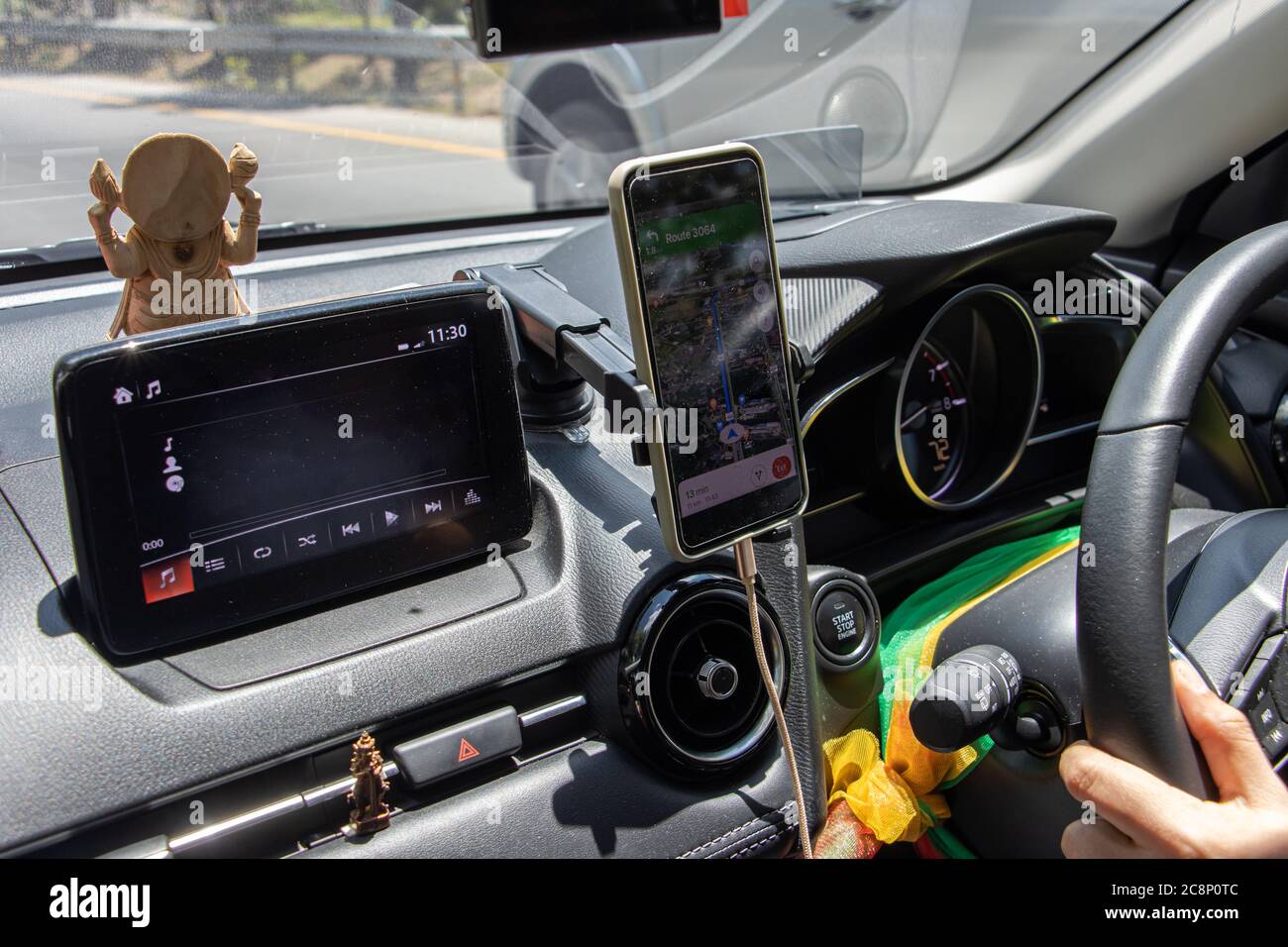 Guida DI un'automobile sull'autostrada, Tailandia. Cruscotto per auto con display del lettore musicale e sistema di navigazione nello smartphone, allacciare il kit vivavoce. Foto Stock