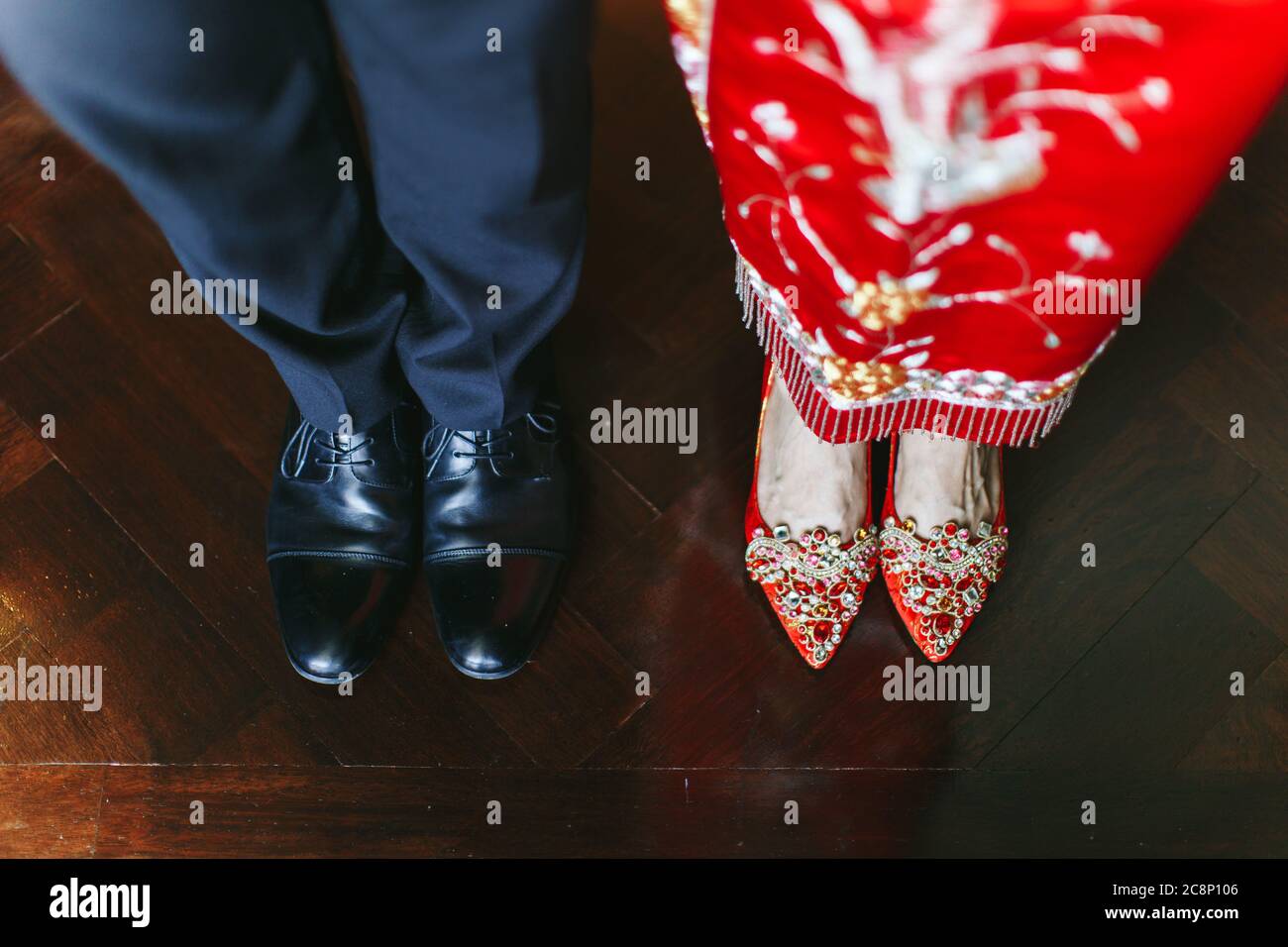 Vista che guarda giù sulle scarpe di sposa e sposo che indossa una miscela di abiti da sposa tradizionali cinesi e occidentali Foto Stock