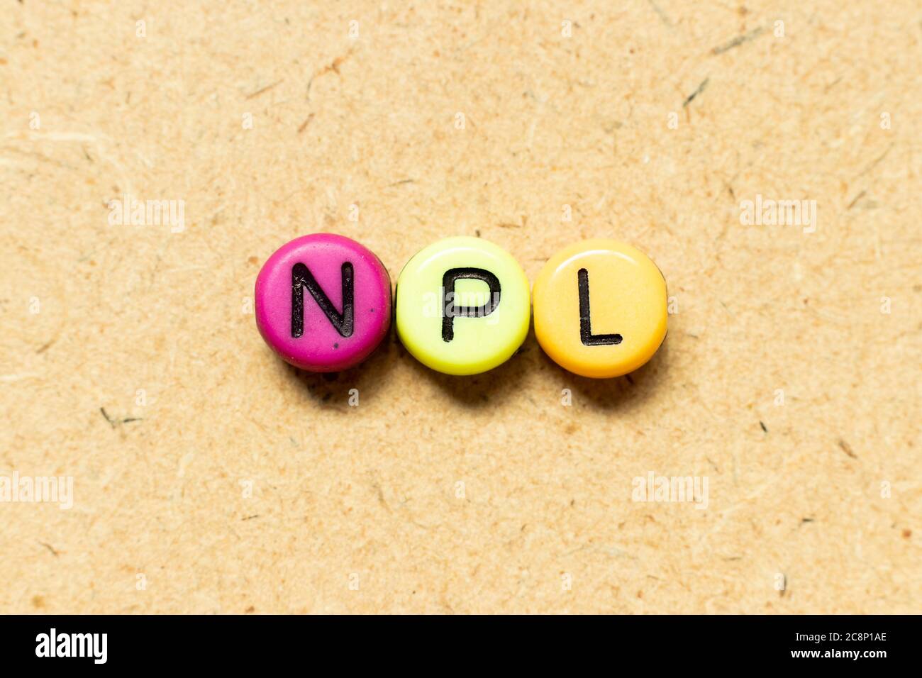 Cordone di colore rotondo con lettera nera nella parola NPL (abbreviazione di prestito non performante, letteratura non brevettuale) su sfondo di legno Foto Stock