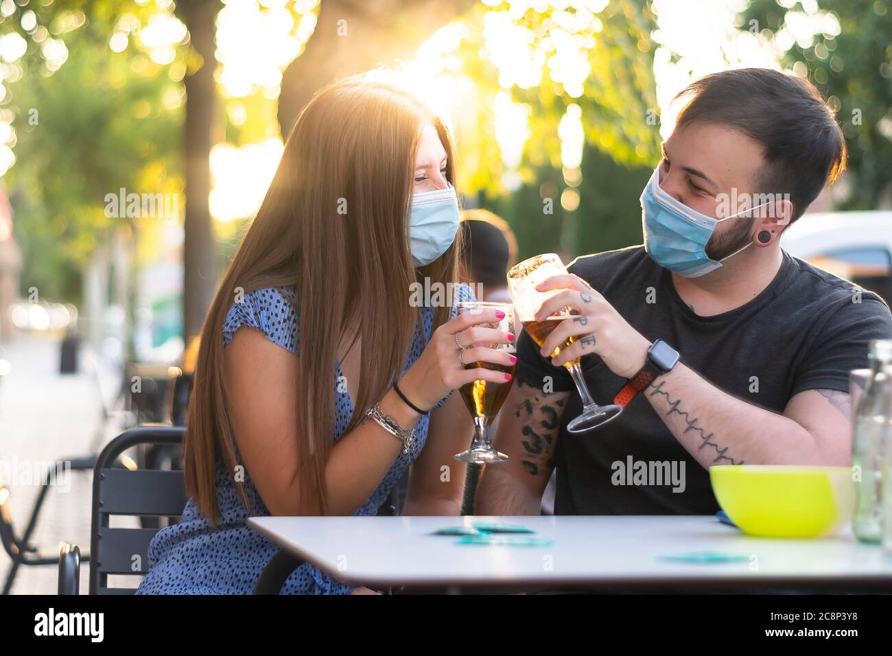 Spagna Madrid. Tostatura di coppia caucasica con birra che indossa una maschera sanitaria. Riaprire pub e club dopo quarentine coronavirus Covid-19. Uomo e donna dri Foto Stock