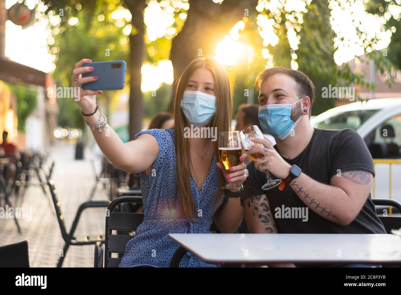 Spagna Madrid. Coppia caucasica tostatura con birra indossando maschera sanitaria prendendo un selfie. Riaprire pub e club dopo quarentine coronavirus Covid-19. M Foto Stock