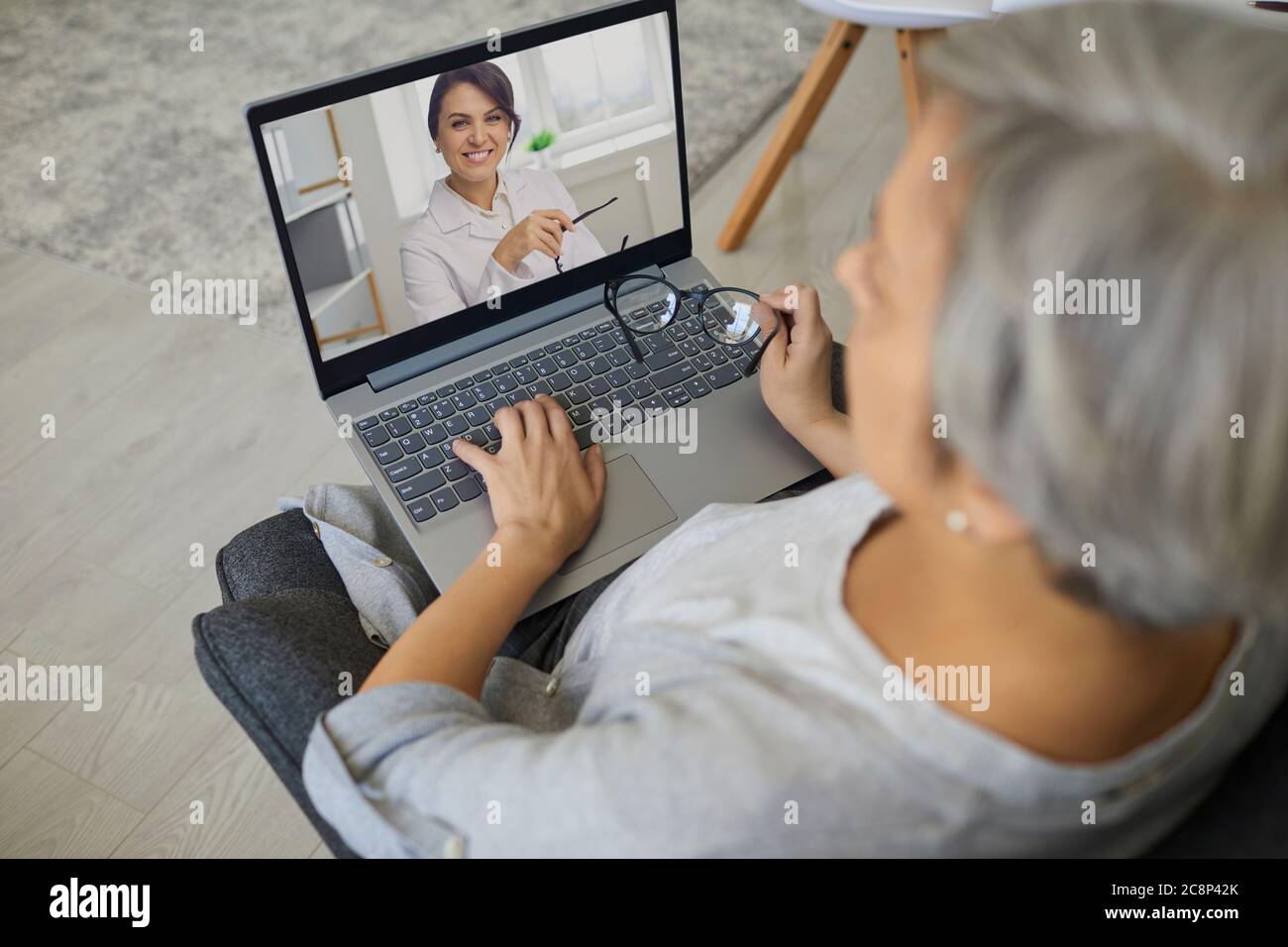 Medico online. Vista sopra di paziente anziano che parla con il medico in linea da casa. Donna matura che consulta con GP su notebook Foto Stock