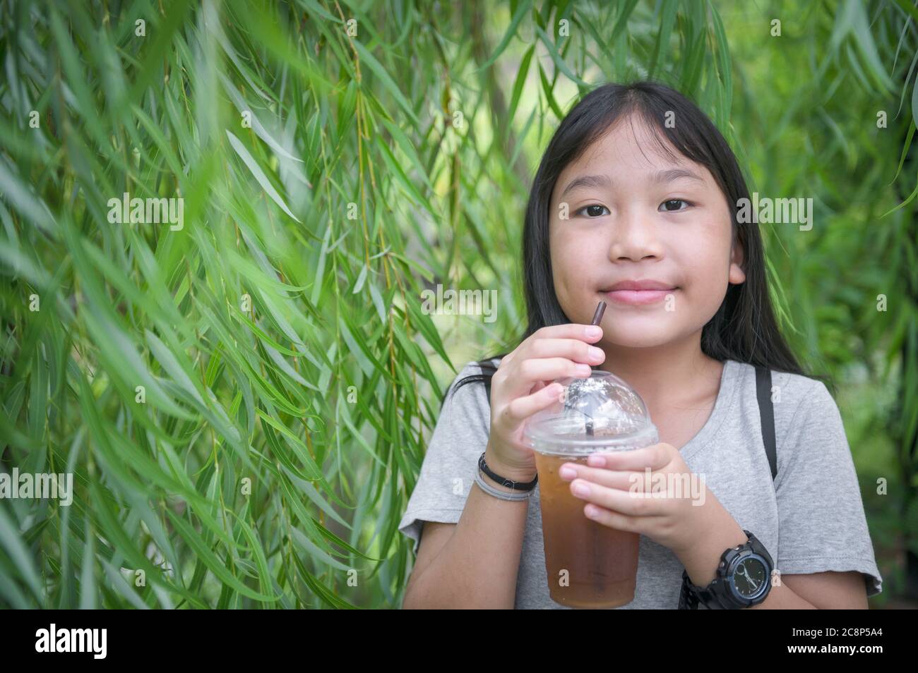 Felice ragazza carina bere miele e tè al limone con ghiaccio su sfondo natura, concetto di bevanda Foto Stock