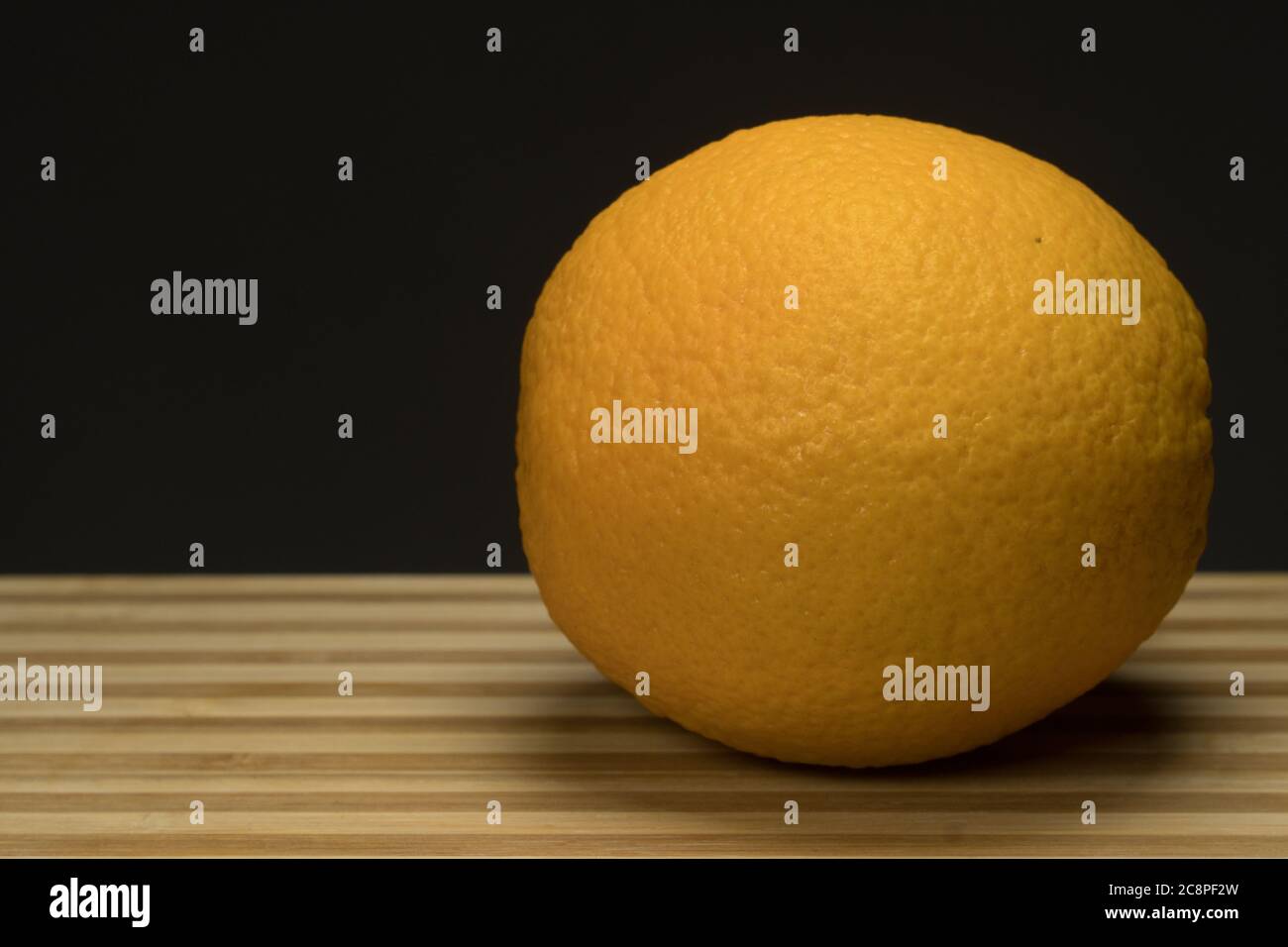 Tre arancione fresco su vassoio di legno circolare con scuro Foto Stock