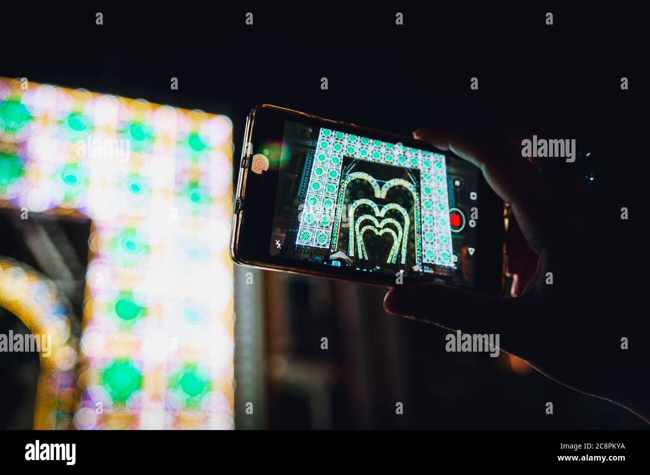 Performance leggera e musicale registrata con uno smartphone tenuto da una mano di donna durante il Cuneo illuminata, tradizionale fiera pubblica in Foto Stock