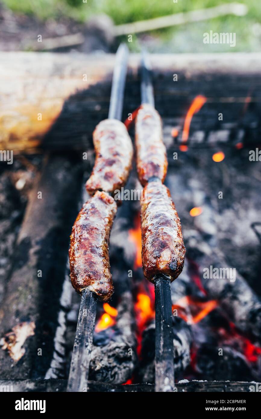 Salsiccia rustica grassa su bastoni sopra il fuoco - barbecue all'aperto Foto Stock